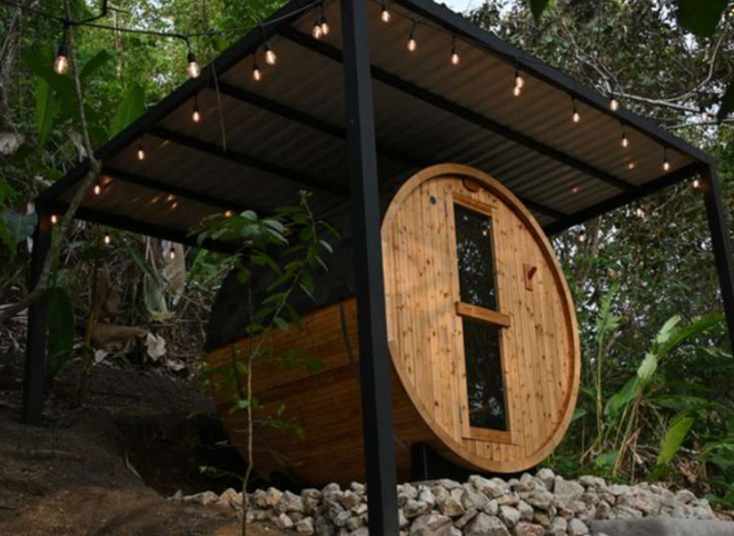 Wooden barrel sauna nestled in lush tropical foliage at a Costa Rica retreat villa